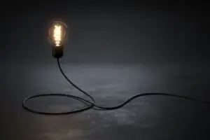 A lit lightbulb on a dark background.